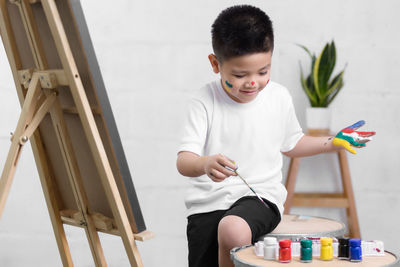 Side view of boy painting on canvas at home