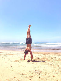 Full length of shirtless man on beach against sky