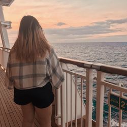 Rear view of woman standing by railing against sea