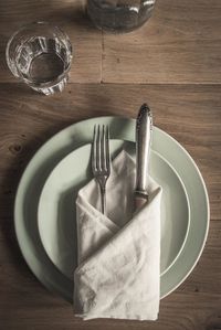 Directly above shot of fork with napkin in plate on wooden table