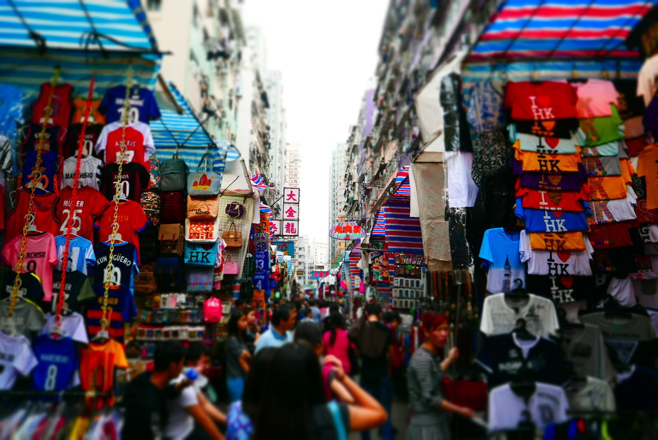 architecture, built structure, large group of people, building exterior, person, men, city, street, city life, walking, lifestyles, crowd, leisure activity, market, building, mixed age range, red, city street, flag