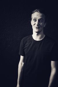 Portrait of a smiling young man against black background