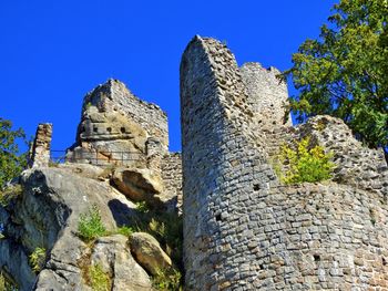 Low angle view of old ruin building against blue sky