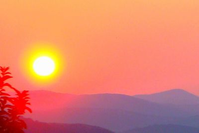 Scenic view of silhouette mountains against orange sky