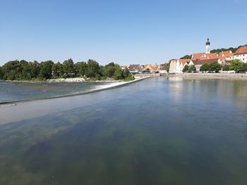 Scenic view of river by buildings against clear sky