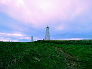 Lighthouse on field against sky
