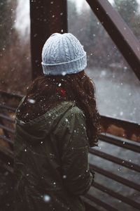 Side view of woman standing on bridge during snowfall