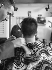 Barber cutting hair of customer in shop