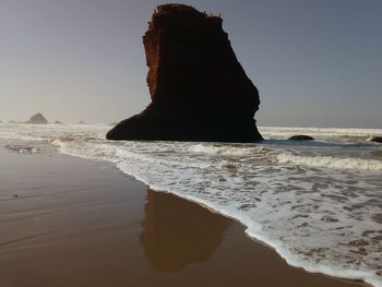 Rock formation on beach against clear sky