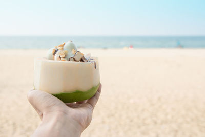 Midsection of person holding ice cream on beach