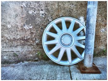 Close-up of old wheel against wall