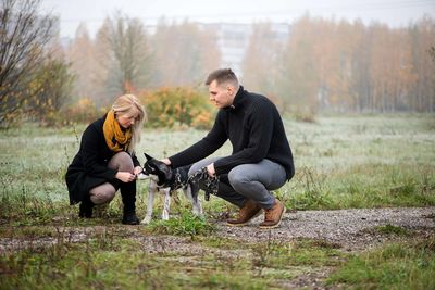 Young happy family couple walking with dog in misty autumn park