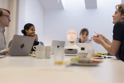 Business people discussing robot voice assistant during meeting