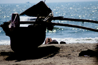 Man holding boat on beach against sky