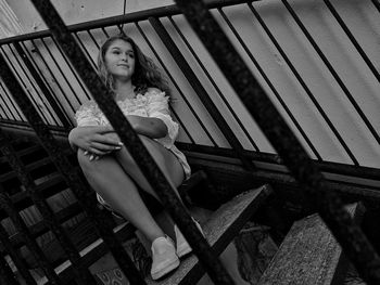 Portrait of woman sitting on railing