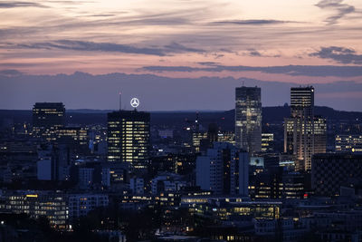 Illuminated buildings in city against sky during sunset