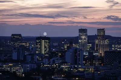 Illuminated buildings in city against sky during sunset