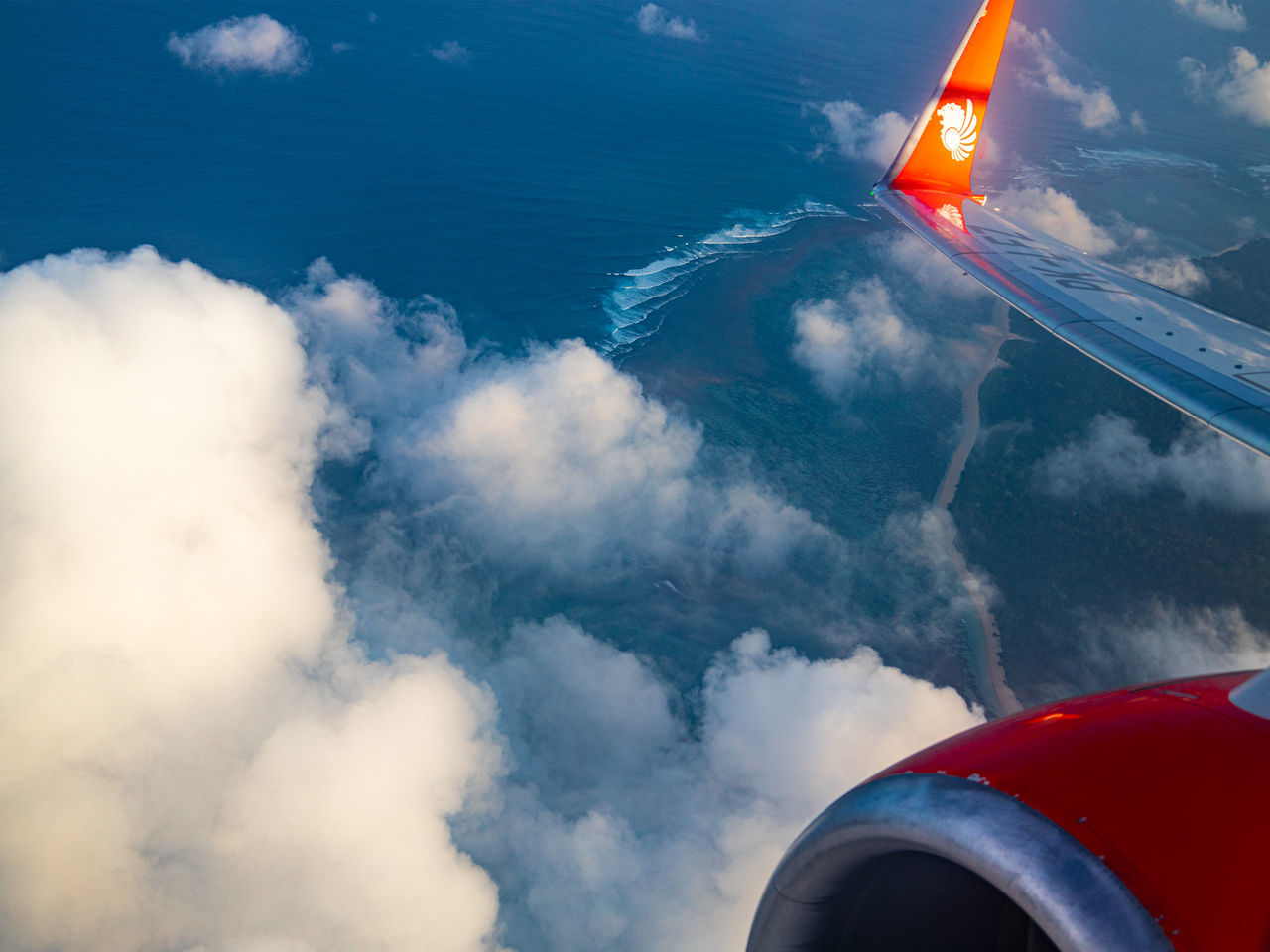 transportation, air vehicle, airplane, cloud, mode of transportation, flying, sky, vehicle, aerial view, nature, blue, travel, aircraft, water, aircraft wing, environment, aviation, no people, red, outdoors, motion, day, wing, sea, mid-air, engine, air travel, wind, cloudscape, journey