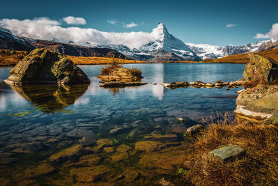 Scenic view of lake by snowcapped mountains against sky