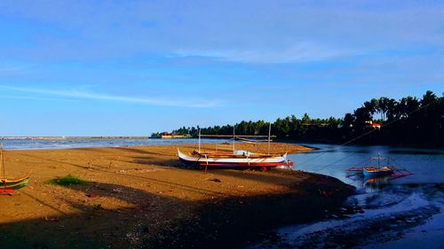 Boats moored on beach against sky