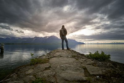 Man standing on rock looking at view of sea against sky