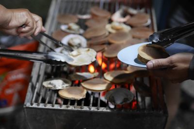 Cropped hands of person grilling food on barbecue grill