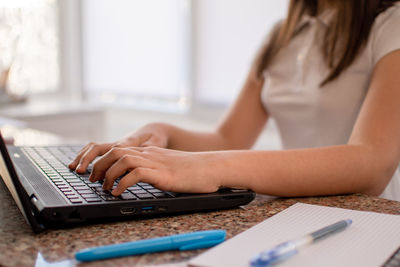 Midsection of woman using laptop at home