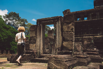 Rear view of woman walking towards old historical building during sunny day