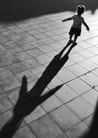 High angle view of girl with arms outstretched standing on footpath