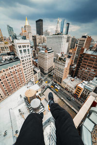 Low section of man and buildings in city against sky