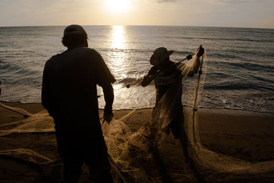 Two people with fishing nets on shore