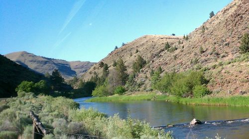 Scenic view of lake and mountains against clear blue sky