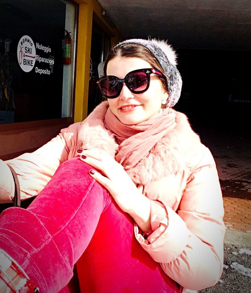 YOUNG WOMAN WEARING SUNGLASSES SITTING ON A OUTDOORS