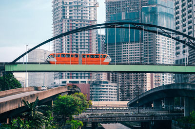 Train on railway bridge against buildings in city
