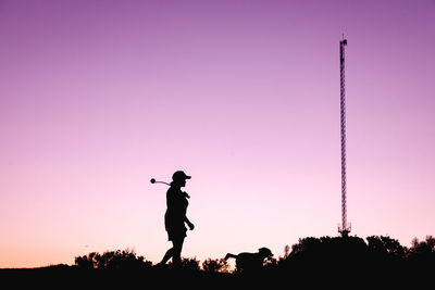 Silhouette woman and a dog standing against pink sky during sunset