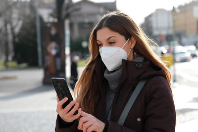 Young woman using mobile phone in winter