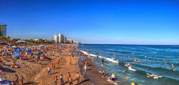 Crowded sands of deerfield beach near the pier with unrecognizable faces in deerfield, florida