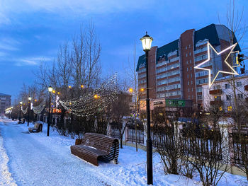 People on snow covered street against sky in city