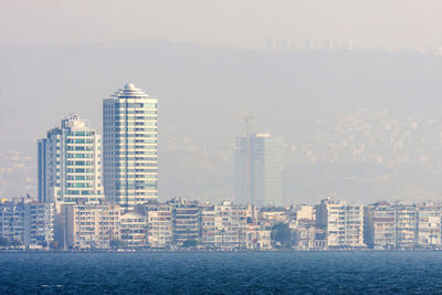 Sea by cityscape against sky