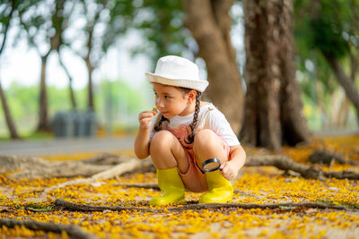 Cute girl wearing hat while sitting on tree