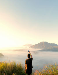 Rear view of man photographing against sky