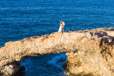 Woman standing on rock by sea