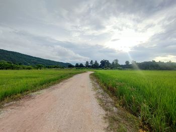 Road amidst field against sky