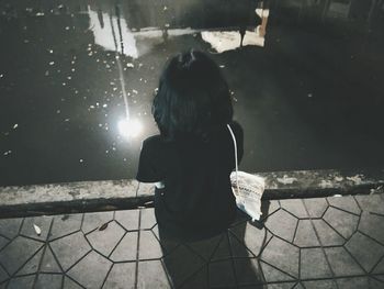 Rear view of woman with arms raised in rainy season