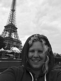 Portrait of smiling mid adult woman in city against cloudy sky