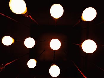 Low angle view of illuminated light bulbs hanging from ceiling
