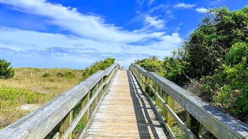 Surface level of wooden bridge against sky