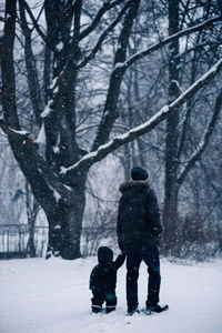 Father holding baby daughter hand while walking on snow covered land