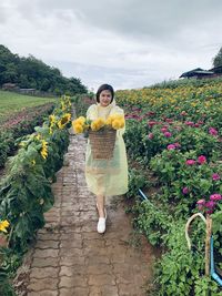 Portrait of woman standing by flowering plants