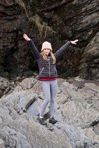 Portrait of girl with arms raised standing on rock formation